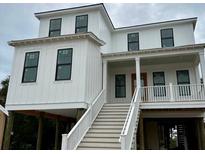 Two-story home with white siding, black windows and a white staircase at 615 Pompano St, Edisto Island, SC 29438
