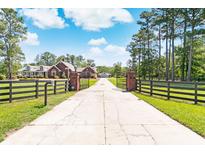 Long driveway leading to a brick home with black fence at 1426 Sc-45, McClellanville, SC 29458