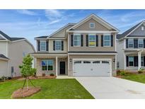 Two-story beige house with a large white garage door and a landscaped lawn at 115 Ashley Cove Way, Summerville, SC 29483