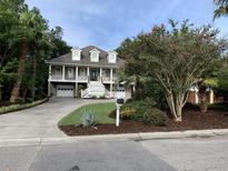 Two-story house with a large front porch, driveway, and landscaped yard at 7 Seahorse Ct, Isle of Palms, SC 29451