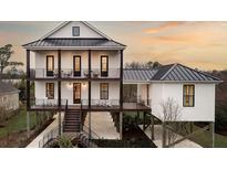 Two-story home with dark metal roof, white siding, and elevated foundation at 66 Cooper St, Charleston, SC 29403