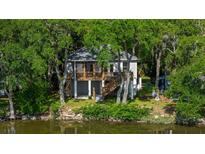 Elevated home on waterfront property with lush green surroundings at 8541 Oyster Factory Rd, Edisto Island, SC 29438