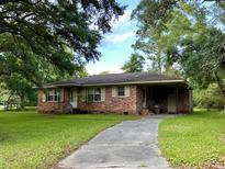 Brick ranch house with a driveway and mature trees at 1236 Midvale Ave, Charleston, SC 29412