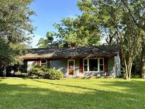 Gray house with red shutters, nestled amongst lush green trees at 1531 Inland Ave, Charleston, SC 29412