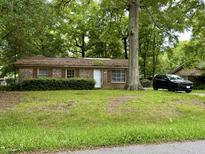 Brick ranch home with mature trees and a black SUV in the driveway at 2615 Myrtis Ln, North Charleston, SC 29406