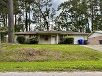 Brick ranch house with a double door entry, a single car garage, and a grassy yard at 7629 Crossgate Blvd, North Charleston, SC 29420