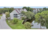 Aerial view of waterfront property with houses and a pond at 202 Mariners Cay Dr, Folly Beach, SC 29439