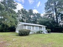 Ranch style home with gray siding, metal roof and landscaped yard at 313 Pine Needle Rd, Walterboro, SC 29488