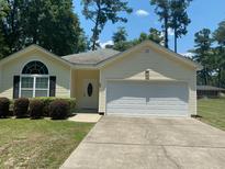 Charming yellow house with a white garage door and well-manicured lawn at 422 Constance St, Walterboro, SC 29488