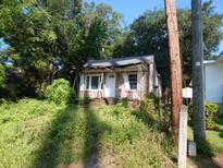 Small brick home with damaged roof and overgrown vegetation at 106 Graham Ln, Summerville, SC 29483