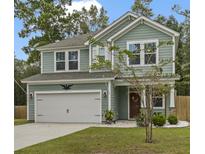 Two-story house with green siding, white garage door, and landscaping at 316 Bay Village Ln, Moncks Corner, SC 29461