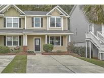 Tan and green two-story townhome with a black door, landscaping, and a concrete driveway at 116 Hidden Palms Blvd, Summerville, SC 29485