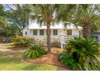 Charming white cottage with lush landscaping and a metal roof at 933 Mccants Dr, Mount Pleasant, SC 29464