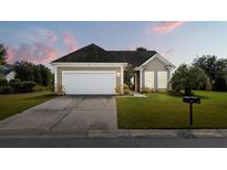Tan house with a white garage door and landscaping at 586 Eastern Isle Ave, Summerville, SC 29486
