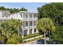 Two-story white house with a balcony, lush landscaping, and a black fence at 106 W Shipyard Rd, Mount Pleasant, SC 29464