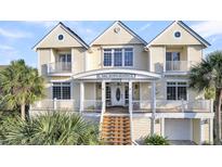 Exterior of charming three-story beach home with large front porch and white railings at 1408 Palmetto Blvd, Edisto Island, SC 29438