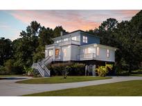 Two-story home with large deck, driveway, and landscaping at 7848 Pelican Bay Dr, Awendaw, SC 29429
