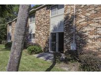 Brick building exterior with sliding glass door leading to a patio, lush landscaping, and palm tree at 809 Andrea Ln, Hanahan, SC 29410