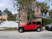 Distressed pink house with boarded windows; red Jeep parked in front at 2 Henrietta St, Charleston, SC 29403