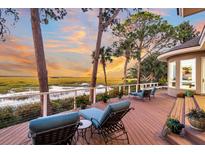 Spacious deck with lounge chairs overlooking tranquil marsh views at sunset at 169 Marsh Island Dr, Kiawah Island, SC 29455