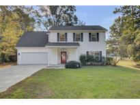 Two-story white house with a red door, attached garage, and manicured lawn at 1600 Windsor Ln, Moncks Corner, SC 29461