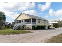Yellow two-story house with screened porch and stairs leading to entrance at 2302 Palmetto Blvd, Edisto Beach, SC 29438