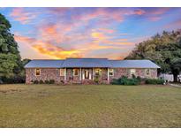 Brick ranch house with metal roof and landscaped yard at 203 Hickory Nut Drive, Harleyville, SC 29448