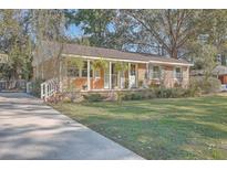 Brick ranch home with covered porch, mature trees, and a spacious yard at 1839 Manigault Pl, Charleston, SC 29407