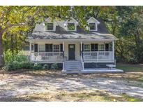 Charming yellow house with a wraparound porch and a well-manicured lawn at 3260 Cohen Hill Rd, Johns Island, SC 29455