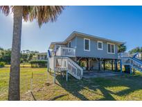 Elevated beach house with a wrap-around porch and large backyard at 3131 Palmetto Blvd, Edisto Island, SC 29438