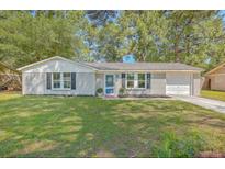 Newly painted grey brick ranch home with a blue door, and a well-manicured lawn at 3264 Stonehaven Dr, North Charleston, SC 29420