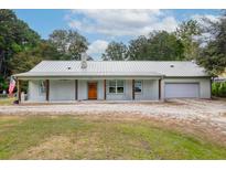 Single story home with metal roof, garage, and covered porch at 3034 Cane Slash Rd, Johns Island, SC 29455