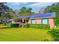 Brick ranch home with solar panels, large yard, and covered porch at 185 Old Fort Dr, Ladson, SC 29456