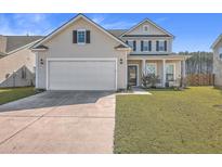 Two-story house with beige siding, white garage door, and manicured lawn at 488 Sanctuary Park Dr, Summerville, SC 29486