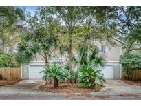 Two-story home with attached two-car garage and lush landscaping at 317 W Hudson Ave, Folly Beach, SC 29439