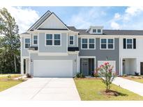 Two-story townhome with gray siding, white garage doors, and landscaping at 569 Trotters Ln # 222, Moncks Corner, SC 29461