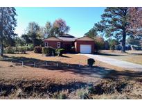 Brick ranch house with attached garage and mature landscaping at 153 Davis Ter, Saint George, SC 29477