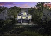 Elevated view of charming two-story home with deck, water views, and sunset at 32 Marsh Island (4 Shares) Ln, Isle of Palms, SC 29451
