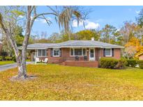 Brick ranch home with a covered porch, and well-manicured lawn at 1216 Fort Dr, Hanahan, SC 29410