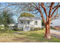 Charming white cottage with a metal roof, front porch, and landscaped yard at 1328 Cottonwood St, Charleston, SC 29403