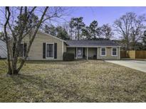 Tan house with dark shutters, covered porch, and a grassy yard at 115 Marion Rd, Summerville, SC 29486