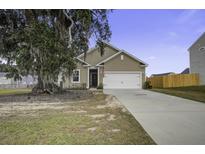 Tan house with a white garage door and a large tree in the front yard at 435 Eva St, Moncks Corner, SC 29461