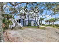Two-story house with wraparound porch, mature trees, and spacious driveway at 67 Lost Village Trl # 9, Edisto Island, SC 29438