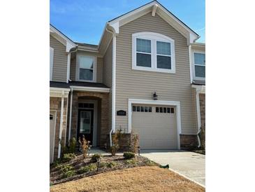 Tan two-story townhome with a two-car garage and landscaping at 12027 Gambrell Dr # 0054, Charlotte, NC 28278