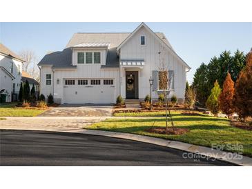 White farmhouse exterior with gray roof, two-car garage, and landscaping at 5723 Heirloom Crossing Ct, Charlotte, NC 28270