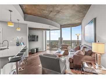 Modern living room with city views, hardwood floors, and a large window at 210 N Church St # 2613, Charlotte, NC 28202