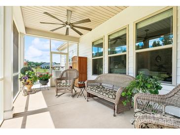 Relaxing screened porch with wicker furniture, ceiling fan, and potted plants at 212 Portrait Way, Indian Trail, NC 28079