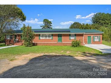 Brick ranch house with a green metal roof and solar panels at 2110 E Greenbriar Rd, Statesville, NC 28625