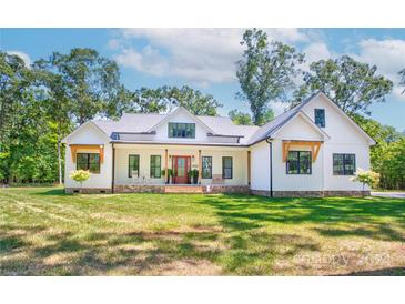 Stunning farmhouse exterior with white siding and stone accents at 14941 Deer Hollow Dr, Gold Hill, NC 28071