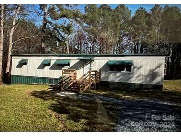 Mobile home with green accents and a wooden staircase at 291 Kendall St, Norwood, NC 28128